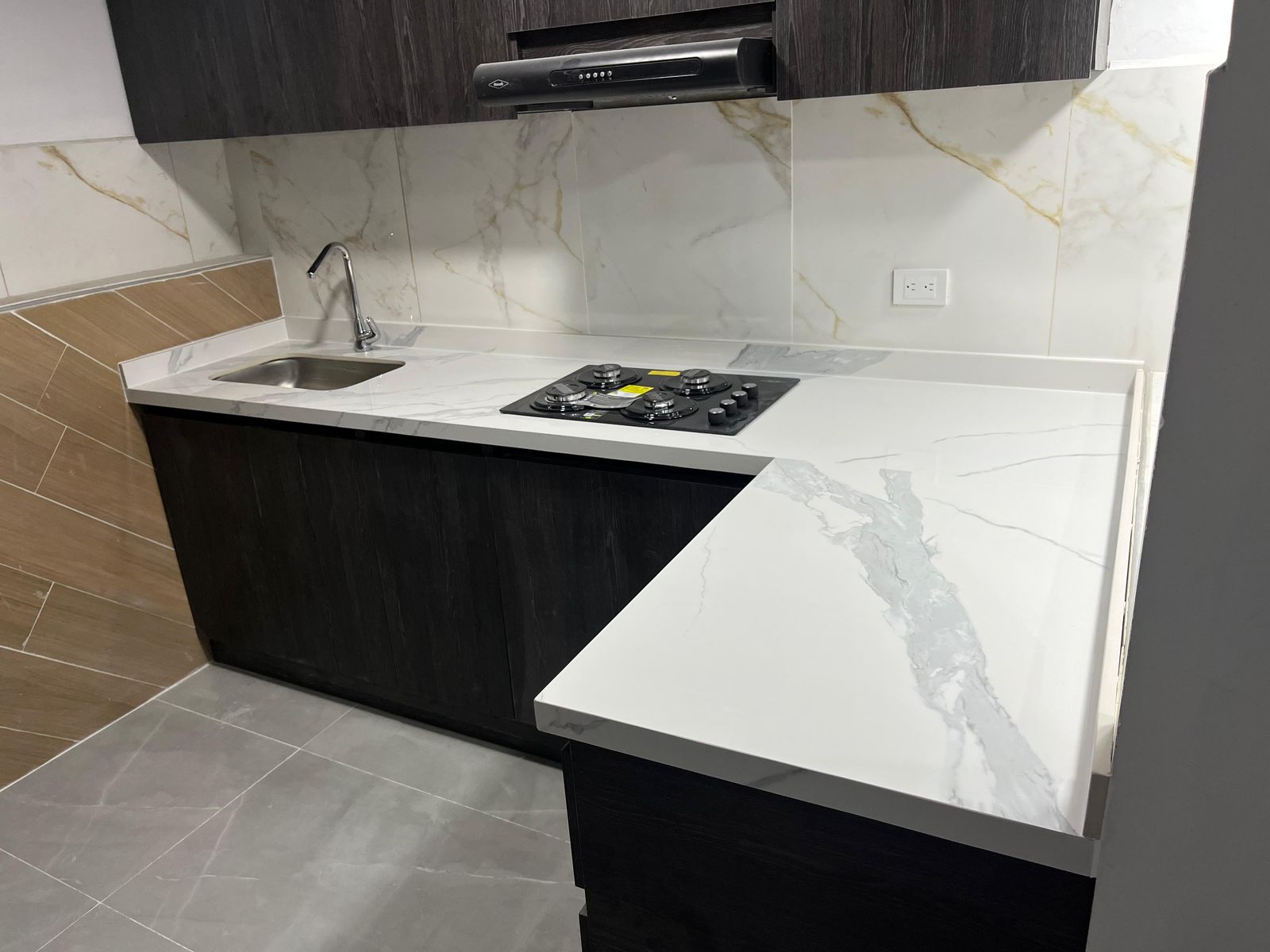 Cocina en L con mesón en sinterizado Calacatta y muebles oscuros